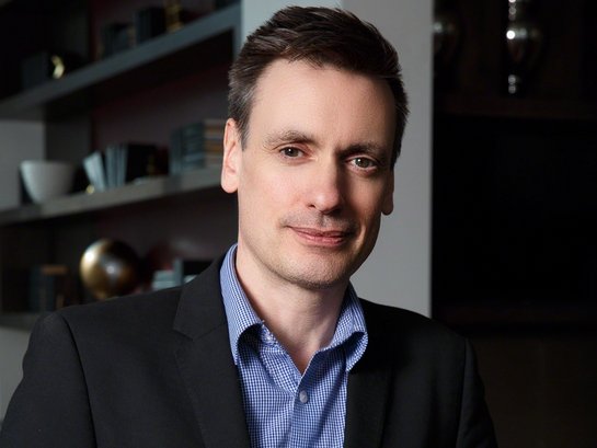 Mike Jones, wearing a blue shirt and smiling in professional photograph.